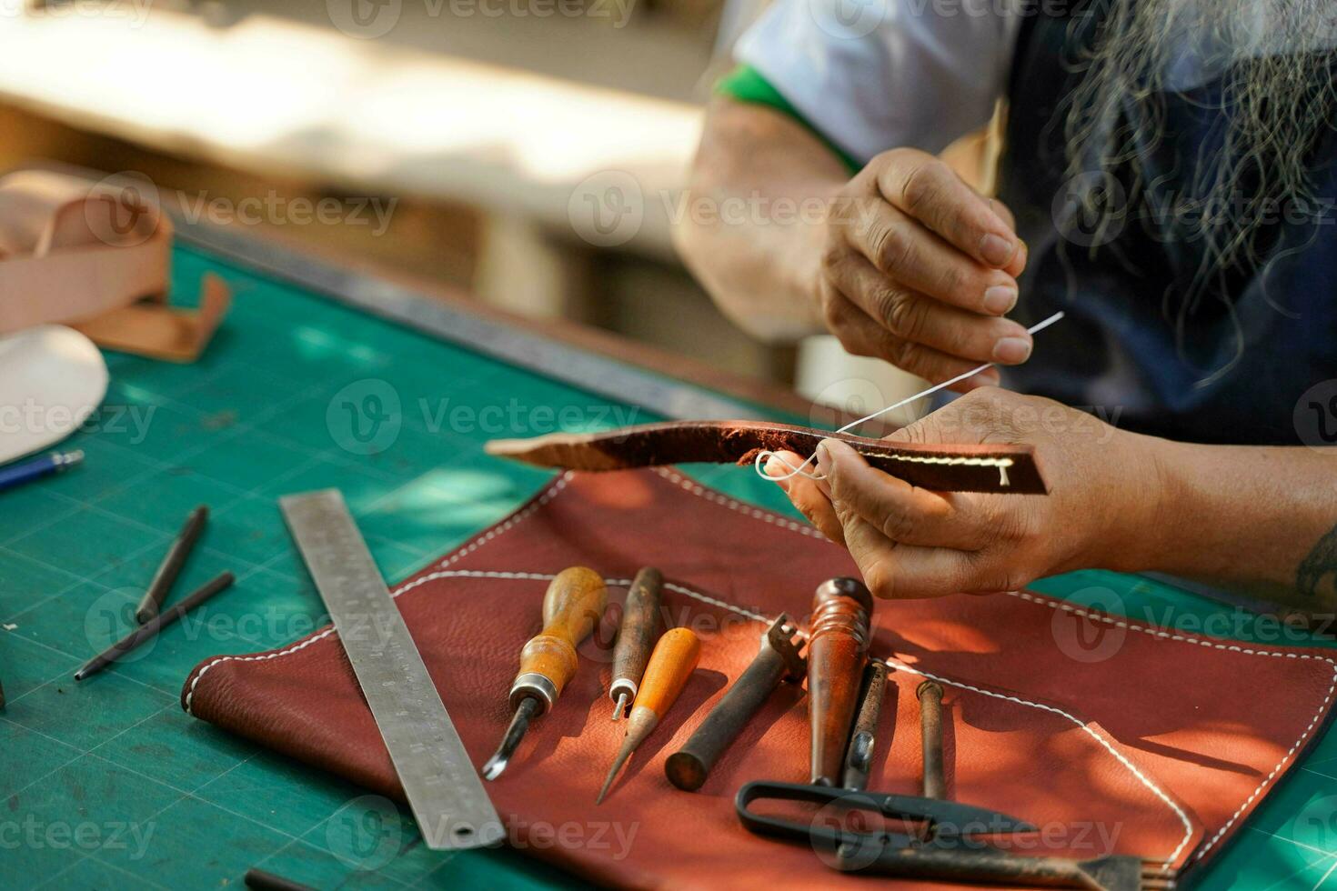 Nahansicht und Ernte Hände von Leder Handwerker ist Arbeiten schwer zu nähen ein Leder Produkt zum ein Kunde. foto