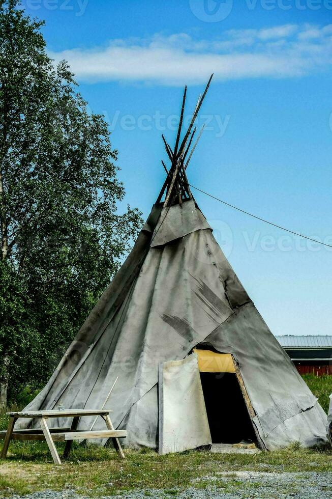 ein Tipi ist Sitzung im das Gras Nächster zu ein Picknick Tabelle foto