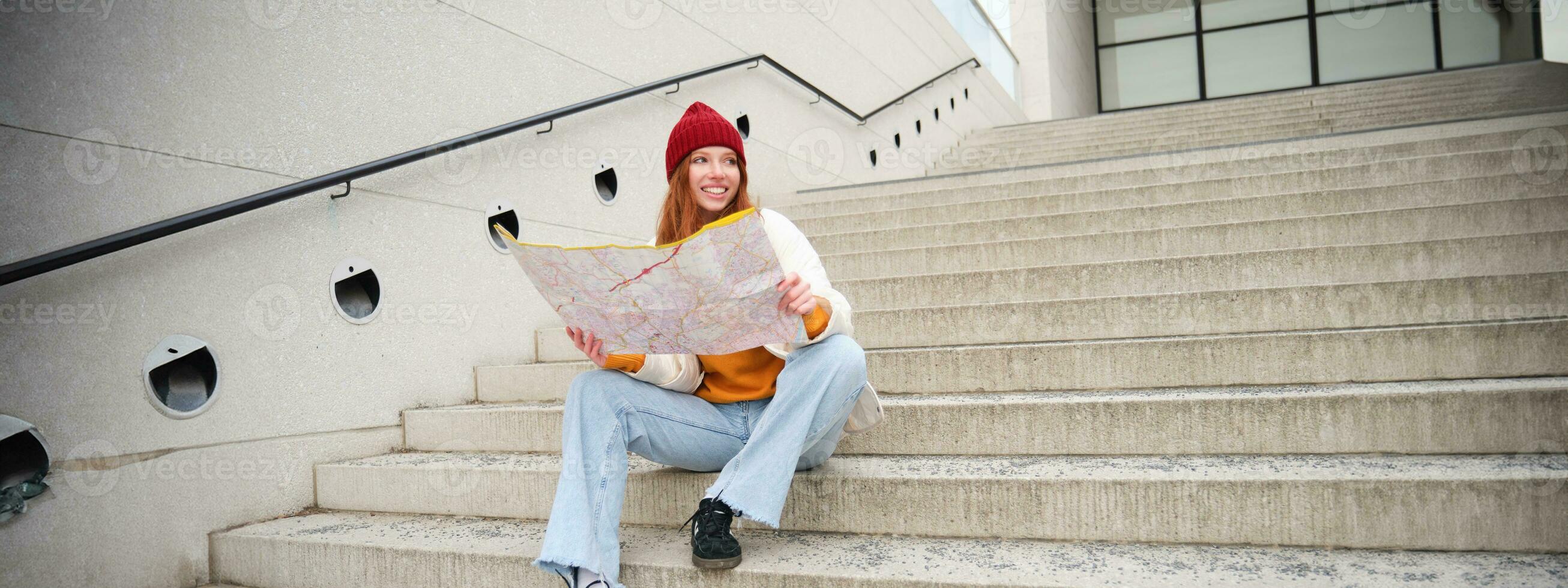 schön Mädchen Tourist sitzt auf Treppe mit Stadt Karte, Pläne ihr Reise, sieht aus zum Richtung während Reisen um Stadt, sucht Route zum Besichtigung foto