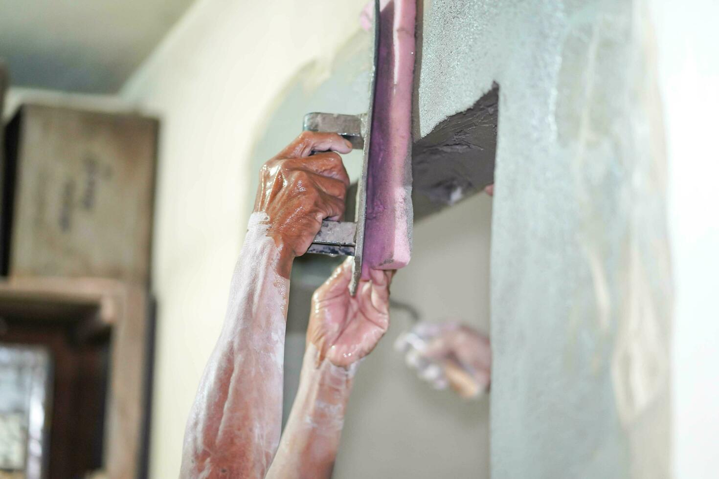Nahansicht Hände von Baumeister halten Granatwerfer schwenken und Schwamm Verputzen Wände mit Zement im Konstruktion Seite? ˅. mit ein Schwamm zu Gips auf das Mauer hilft zu glatt das verputzt Bereich. Mehr schön foto