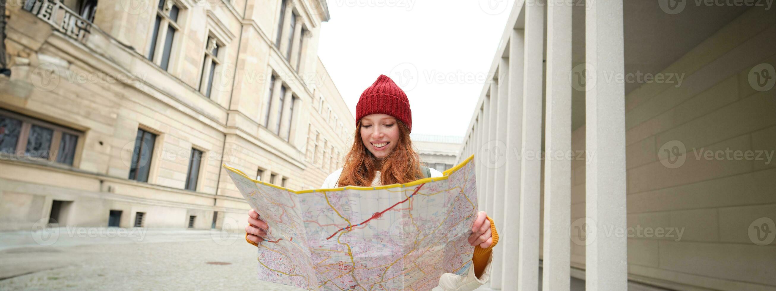 Rothaarige Mädchen, Tourist erforscht Stadt, sieht aus beim Papier Karte zu finden Weg zum historisch Sehenswürdigkeiten, Frau auf ihr Ausflug um Europa sucht zum Besichtigung foto