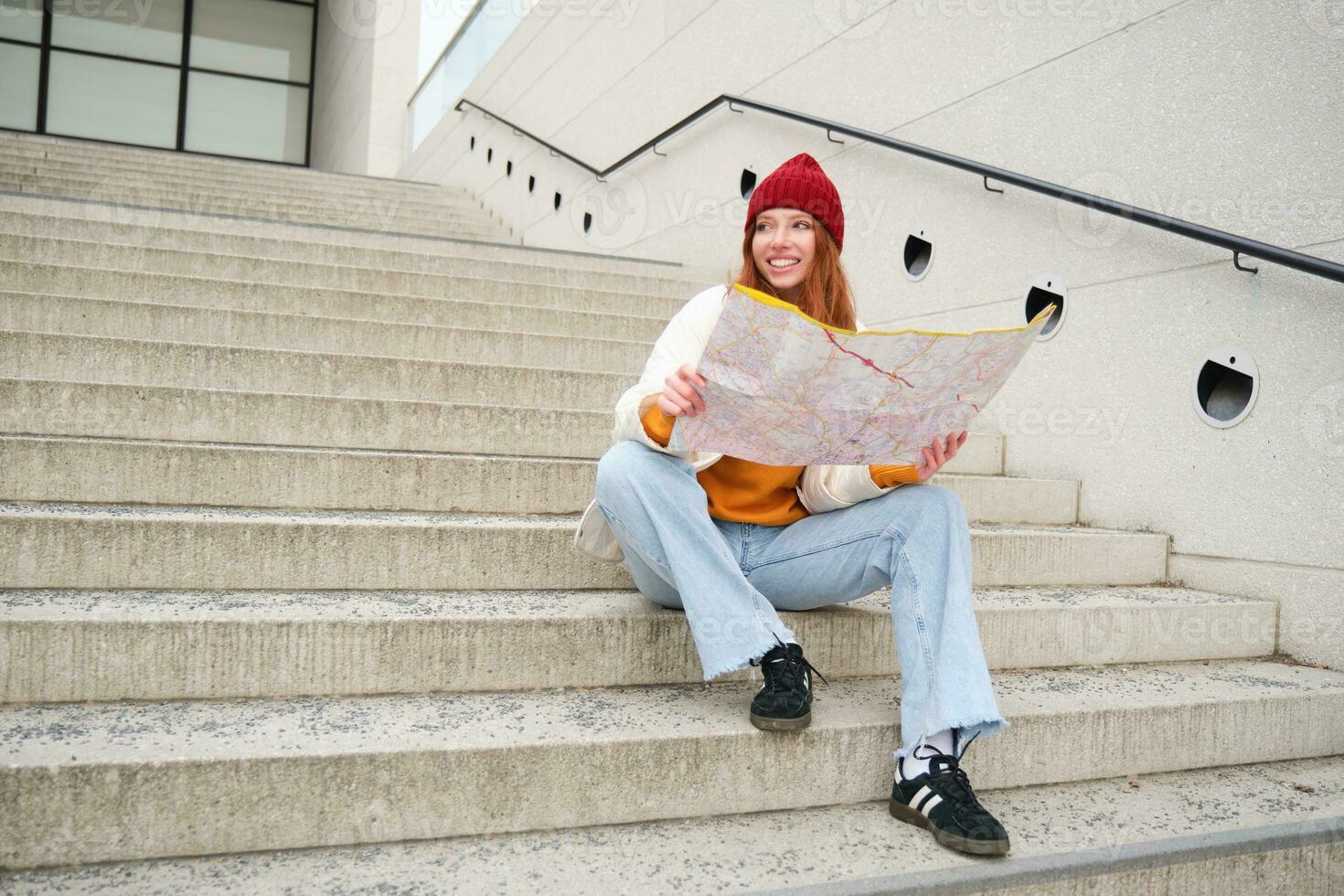 schön Mädchen Tourist sitzt auf Treppe mit Stadt Karte, Pläne ihr Reise, sieht aus zum Richtung während Reisen um Stadt, sucht Route zum Besichtigung foto