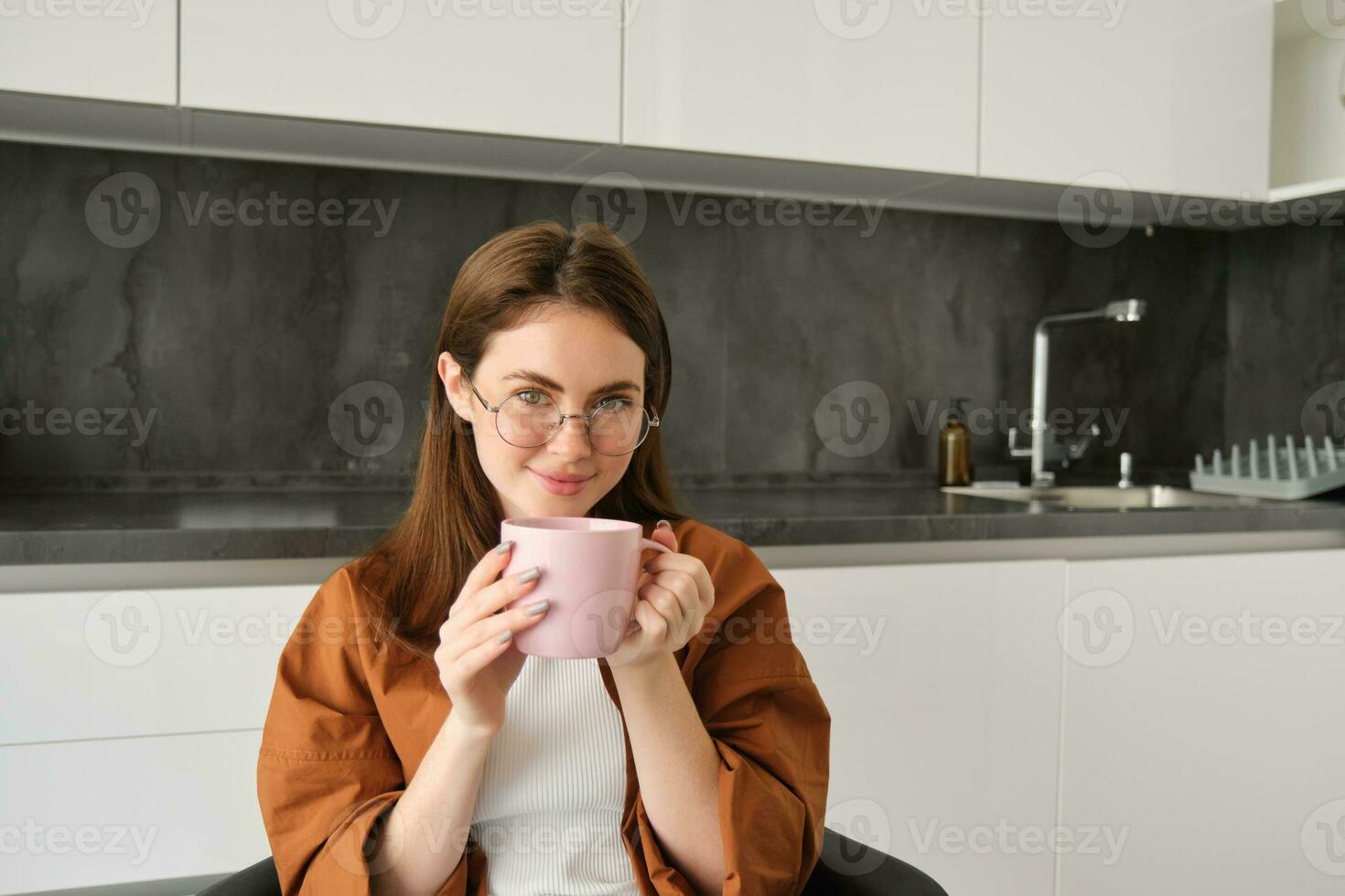 Porträt von schön Frau im Küche, Trinken Kaffee beim heim, Ausgaben Zeit drinnen, genießen gemütlich Tag mit Tasse von entspannend Kräuter- Tee foto