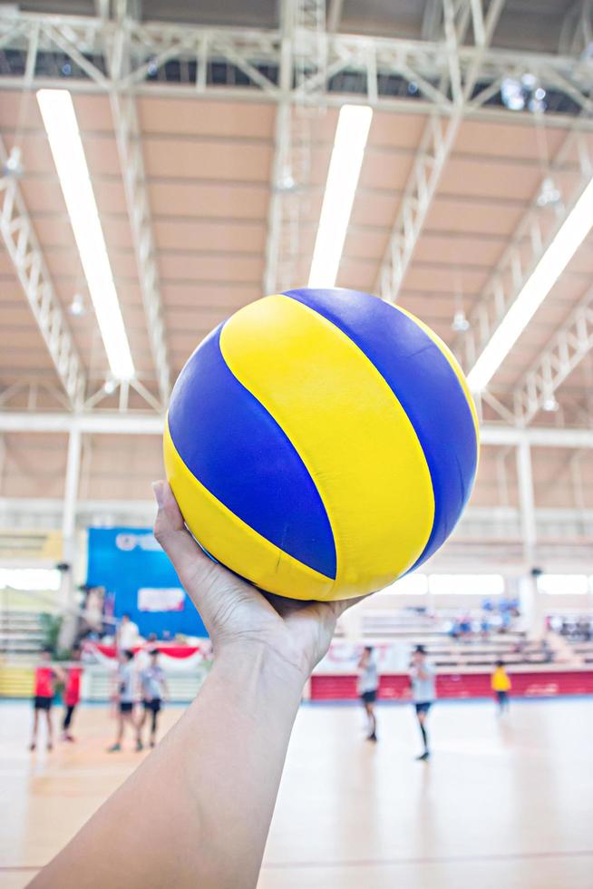 linke Hand hält einen Volleyball für das Volleyballspiel foto