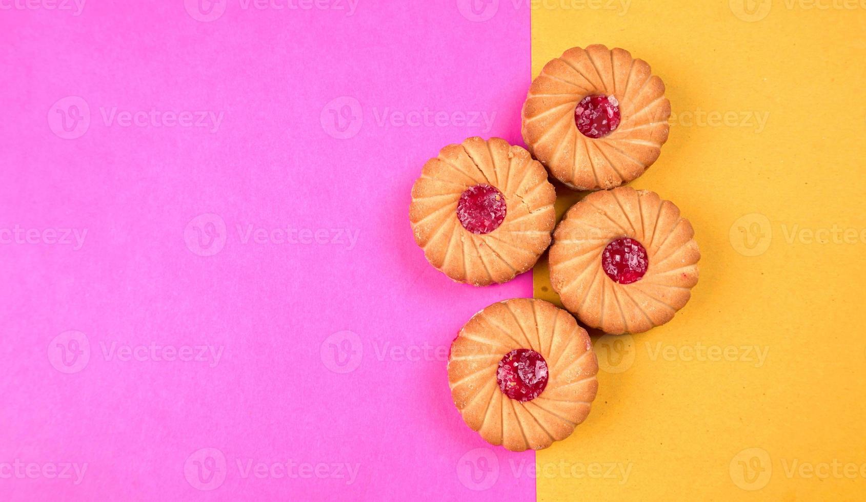 Blick von oben auf die Marmeladenkekse auf rosa und gelbem Hintergrund. Sandwichkekse oder Sahnekekse isoliert. foto