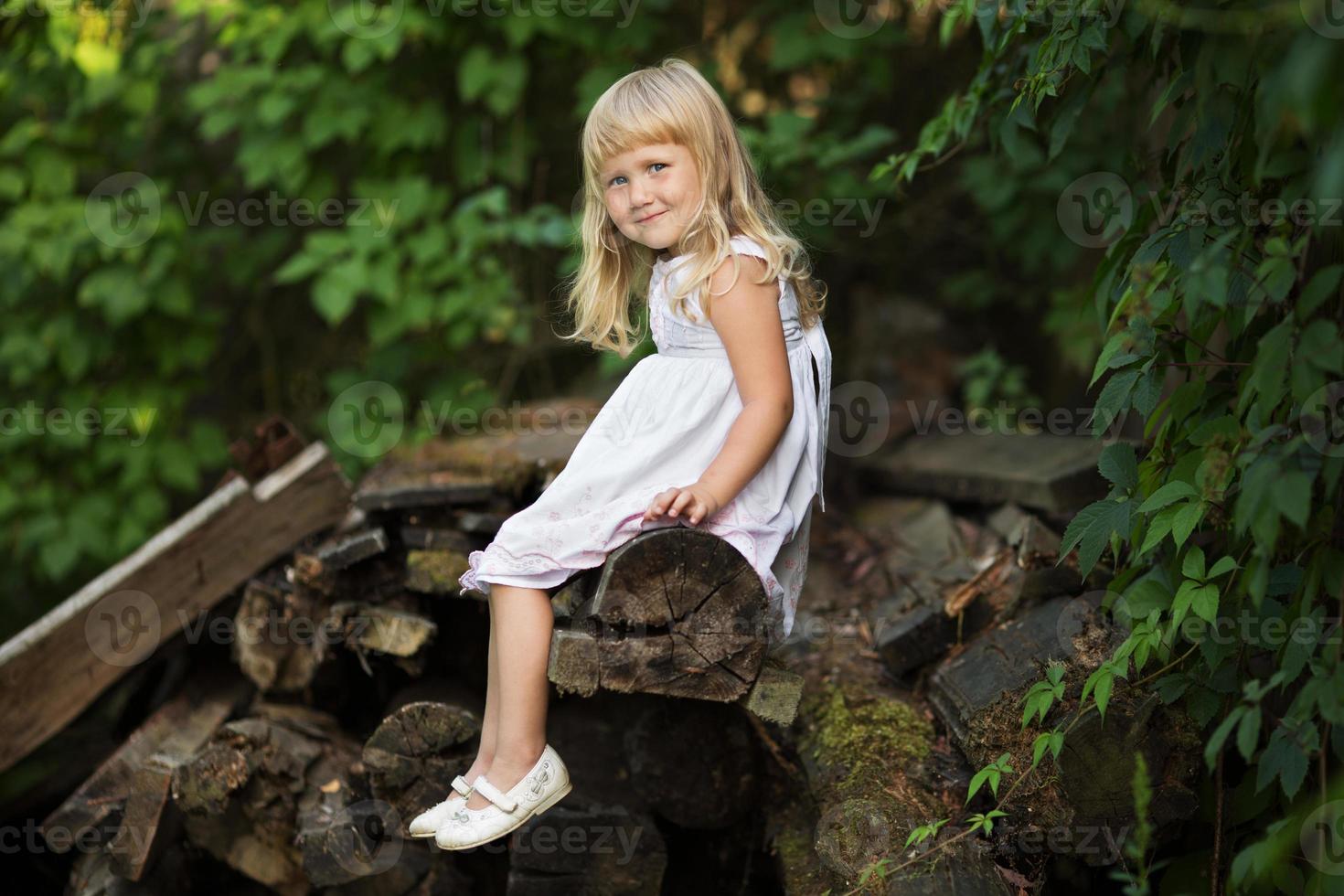 kleines Mädchen sitzt auf alten Brettern foto