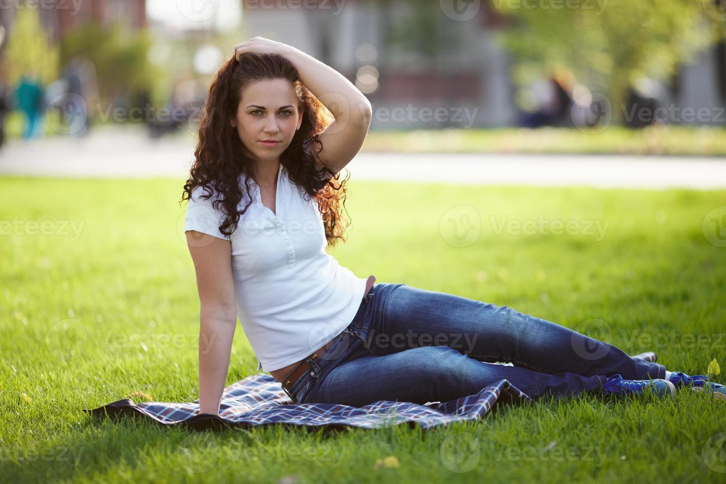 schöne Frau in Jeans sitzt auf dem Gras foto