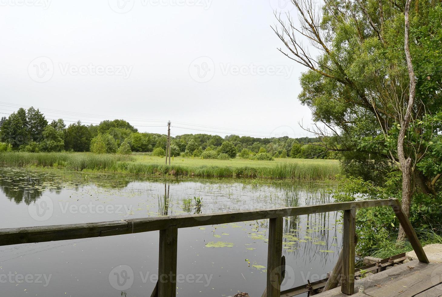 schön stehende alte Holzbrücke über den Fluss in farbigem Hintergrund foto