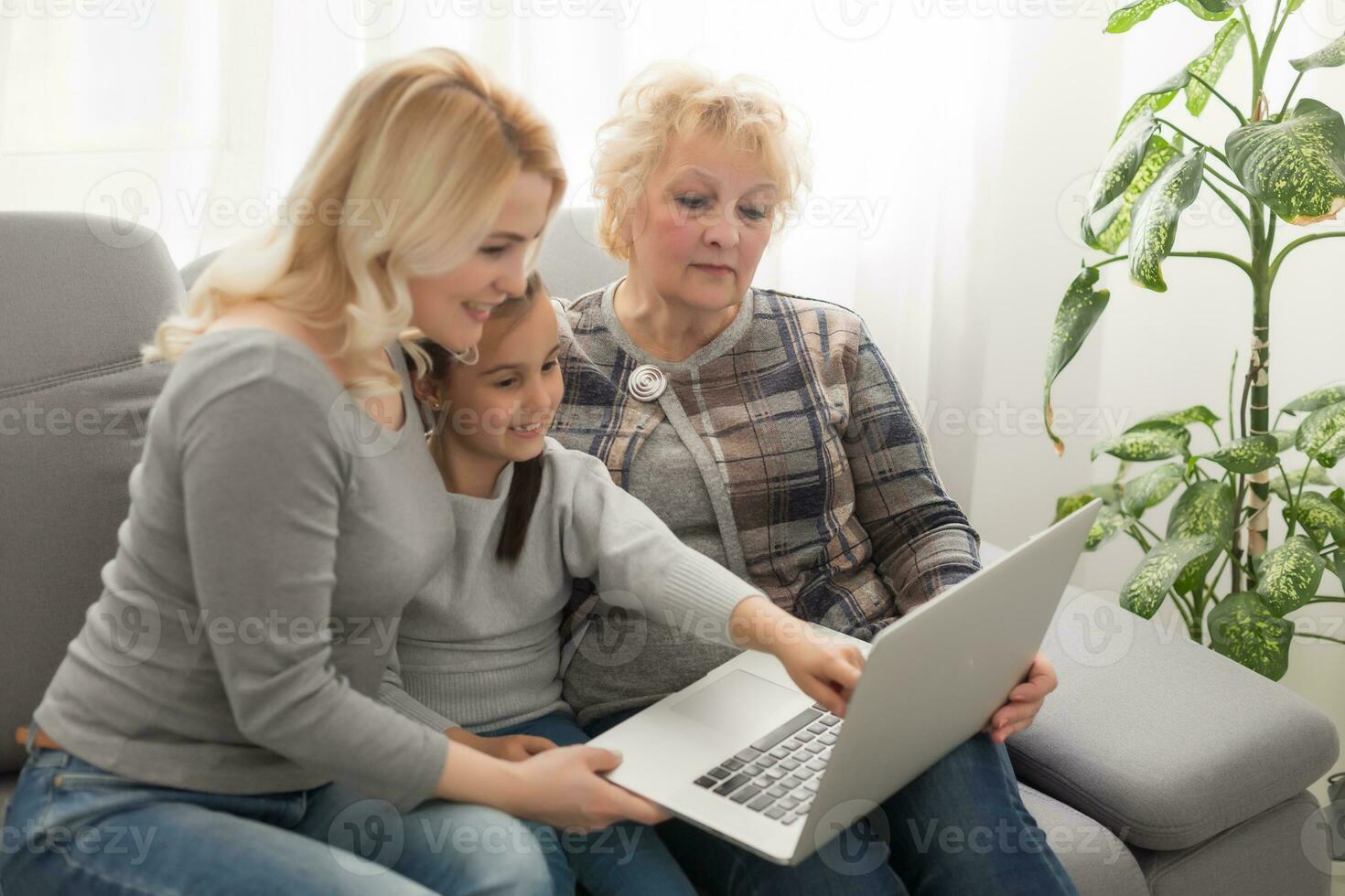 glücklich drei Generationen von Frauen sitzen entspannen auf Couch Lachen Aufpassen komisch Video auf Laptop, lächelnd positiv Frauen Oma, Mutter und Tochter haben Spaß sich ausruhen auf Sofa genießen Film auf Computer foto