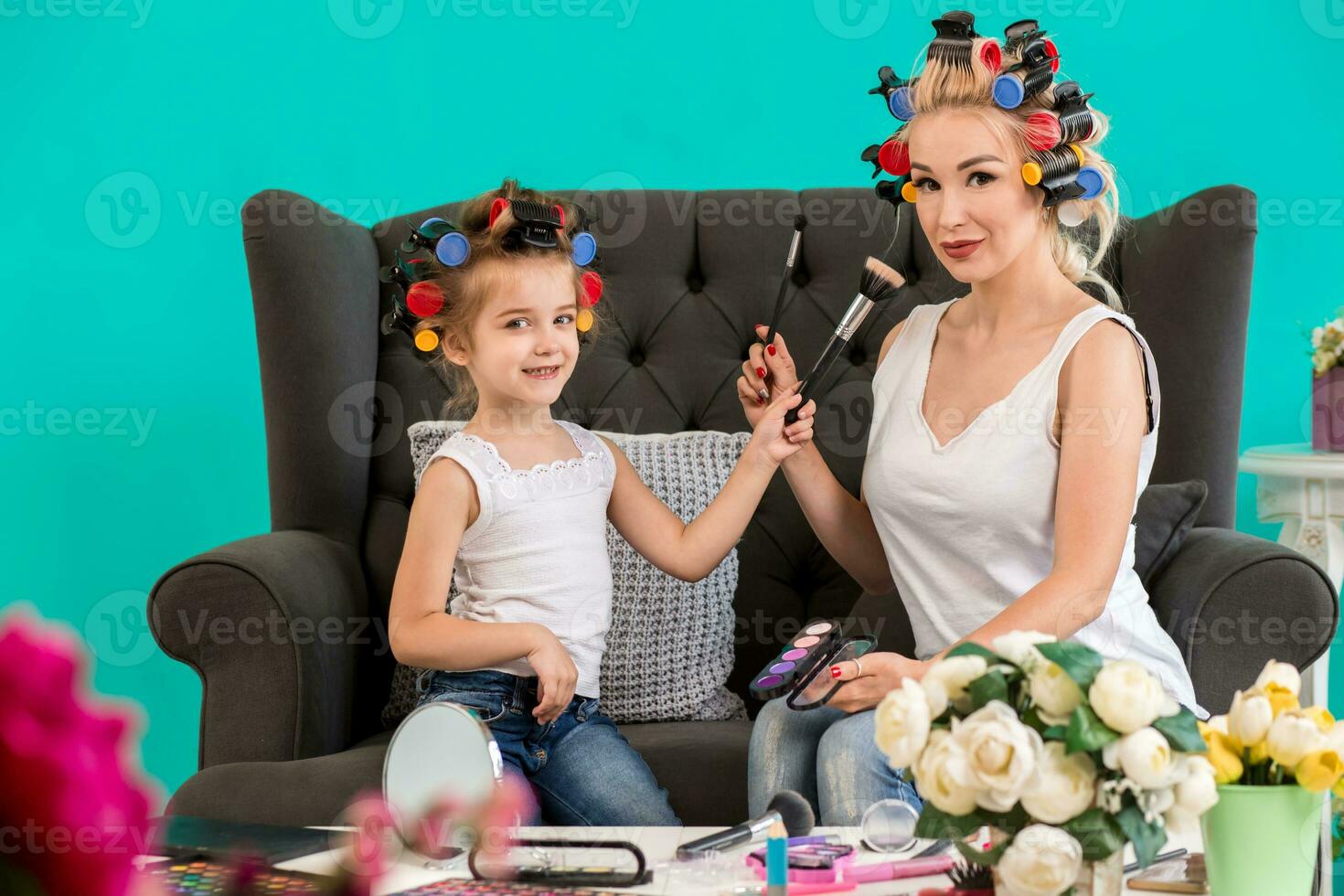 Mama und Tochter im das Studio auf das Sofa im das Lockenwickler machen oben und haben Spaß foto