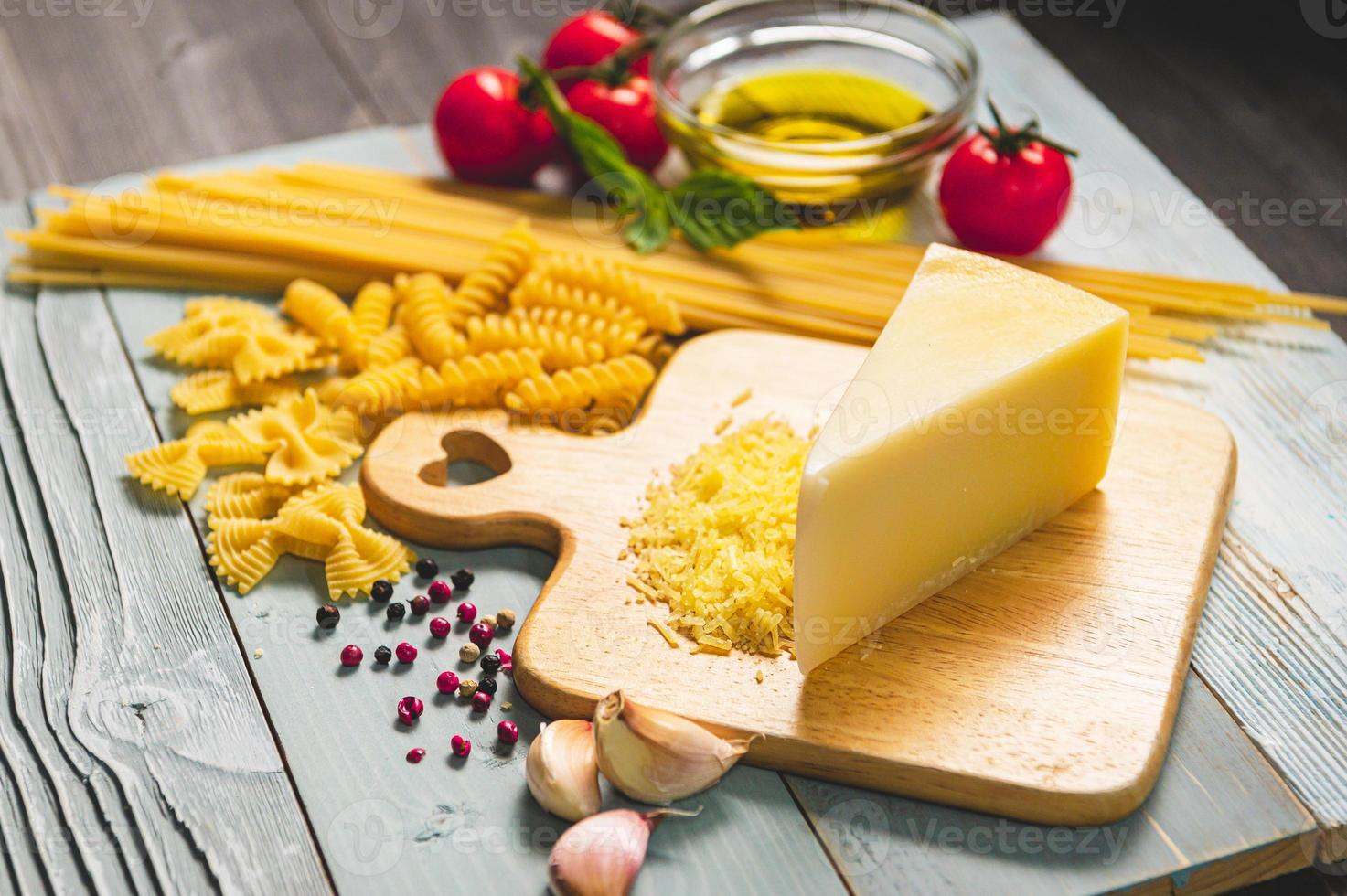 Leckere appetitliche italienische Spaghetti-Pasta-Zutaten für die Küchenküche mit Tomaten, Käse-Parmesan, Olivenöl, Fettuccine und Basilikum auf braunem Holztisch. Essen italienisches Rezept hausgemacht. Ansicht von oben foto