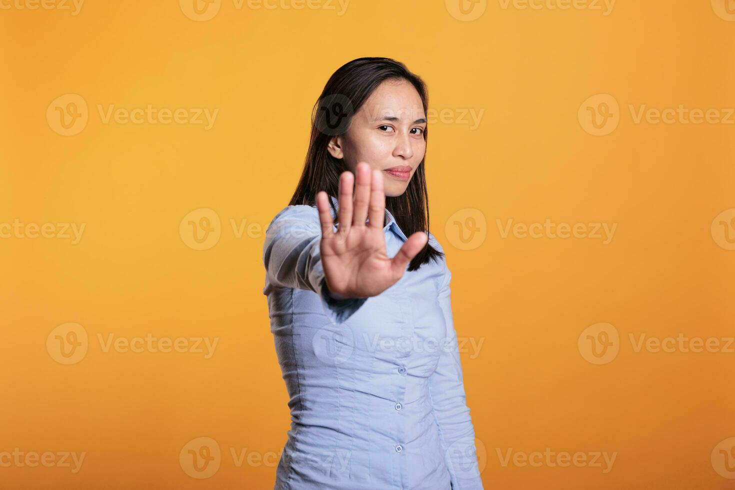 Filipino jung Erwachsene tun Nein Zeichen mit Palme auf Kamera, ausdrücken Missbilligung und Verweigerung. heiter Frau zeigen Ablehnung und Ablehnung Geste Stehen im Studio Über Gelb Hintergrund foto