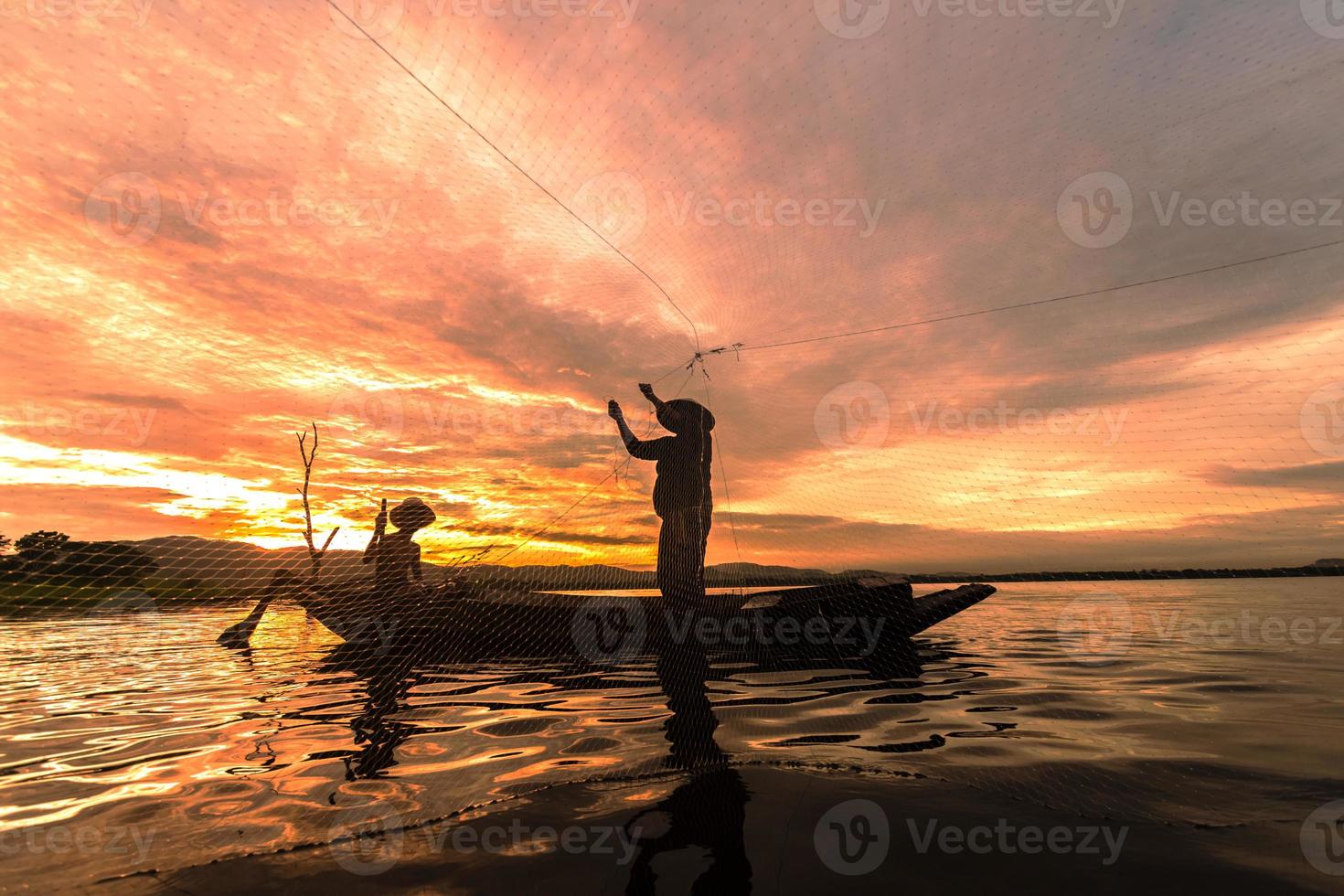 Silhouette Fischerfischen mit Netz auf dem Boot morgens in Thailand, Natur- und Kulturkonzept foto