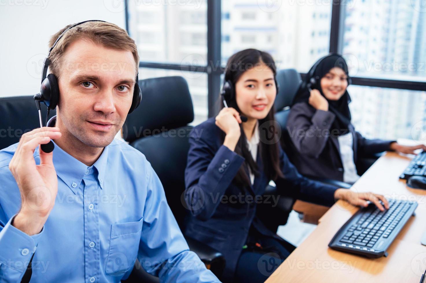 Gruppe junger Berufs-Call-Center-Betreiber mit Headsets, die im Büro arbeiten. Business-Telemarketing-Service-Mitarbeiter, die sich auf die Gesprächsarbeit konzentrieren und kundenfreundlich sprechen foto