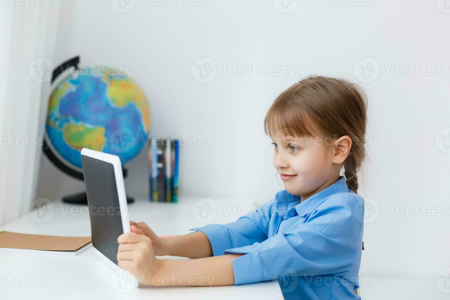 süß wenig Mädchen ist Sitzung beim Tabelle mit ihr Laptop und studieren online foto