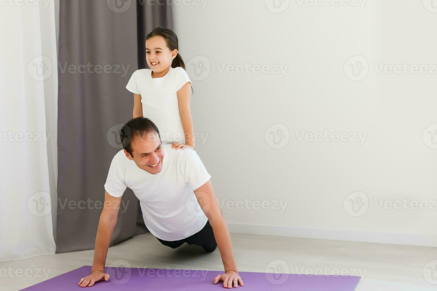 gut aussehend jung Vater und seine süß wenig Tochter sind tun respektieren Planke mit Bein erziehen auf das Fußboden beim heim. Familie Fitness trainieren. foto