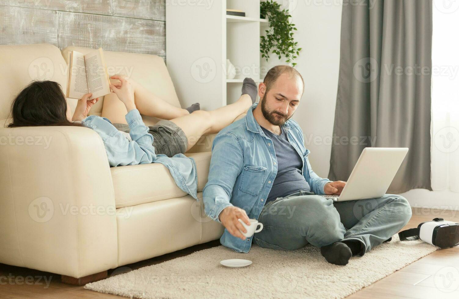 Mann halten Kaffee Tasse während das Ehefrau ist lesen ein Buch. foto