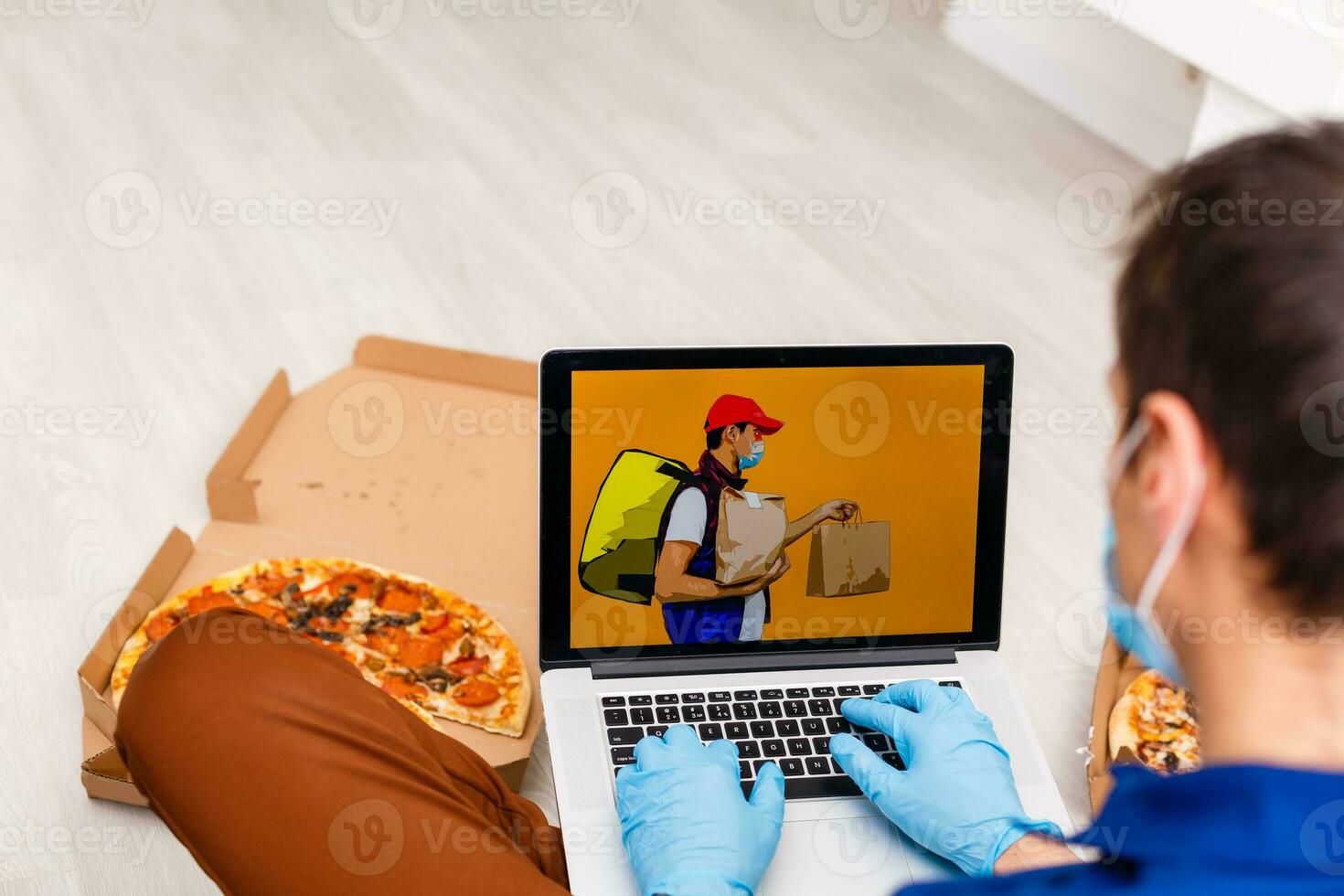 Mann im schützend Handschuhe und Maske mit Laptop zum online Essen bestellen während Quarantäne, Nahaufnahme. Lieferung Bedienung foto