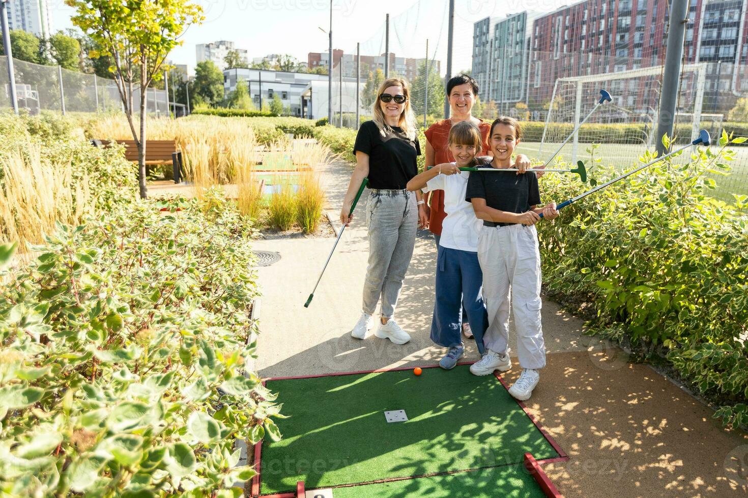 Gruppe von lächelnd freunde genießen zusammen spielen Mini Golf im das Stadt. foto