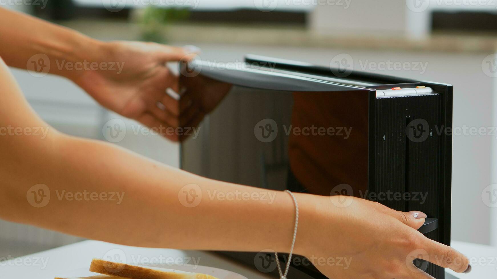 Ehefrau Braten Brot Scheiben auf elektrisch Toaster zum Frühstück Mahlzeit. Hausfrau mit Brot Toaster zum köstlich Frühstück. gesund Morgen im gemütlich Innere, köstlich Zuhause Mahlzeit Vorbereitung foto