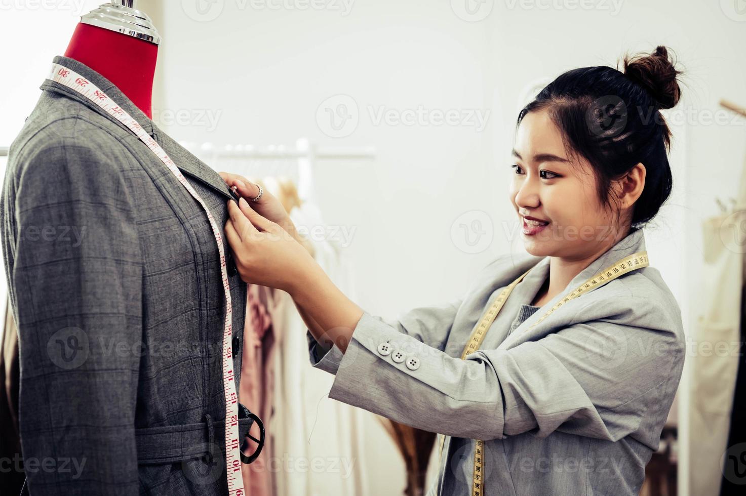 Asiatische Modedesignerin, die sich auf die Uniform des formellen Anzugs auf dem Mannequin-Modell einpasst. Modedesigner stilvoller Showroom. Näh- und Schneiderkonzept. kreative Schneiderin Stylistin foto