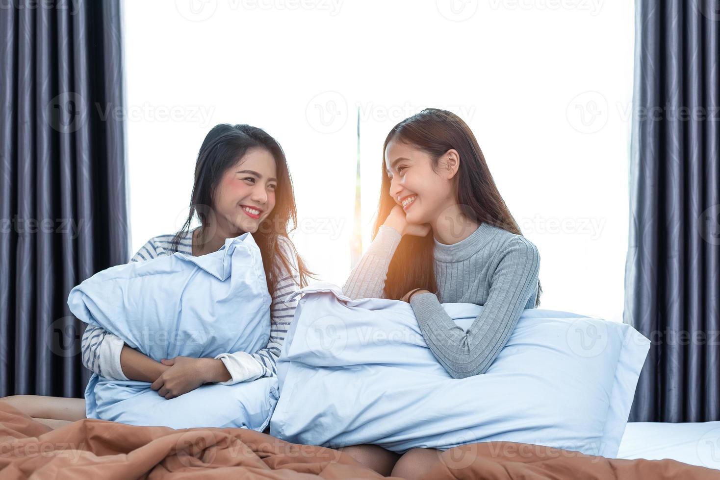 zwei asiatische lesbische frauen, die zusammen im schlafzimmer schauen. paar leute und schönheitskonzept. glücklicher Lebensstil und Home Sweet Home Thema. Kissenkissenelement und Fensterhintergrund foto