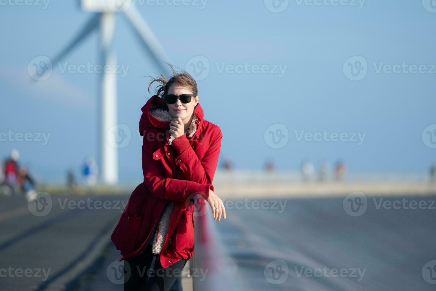 auf das Hintergrund von Windmühlen, ein jung Frau im ein rot Jacke ist genießen ihr Winter Urlaub. foto