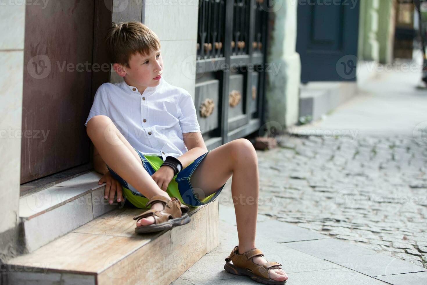 ein traurig nachdenklich wenig Junge sitzt auf das Schritte von das Haus Veranda. psychologisch Porträt von ein nachdenklich Kind. foto