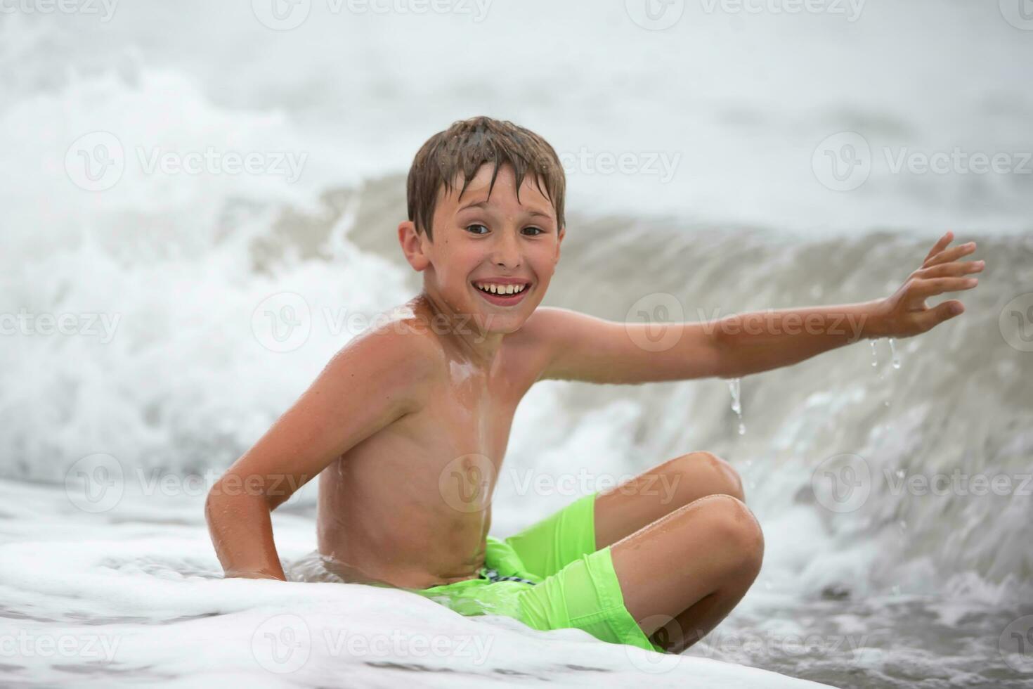 glücklich Junge im ein Meer Welle Baden sieht aus beim das Kamera. foto