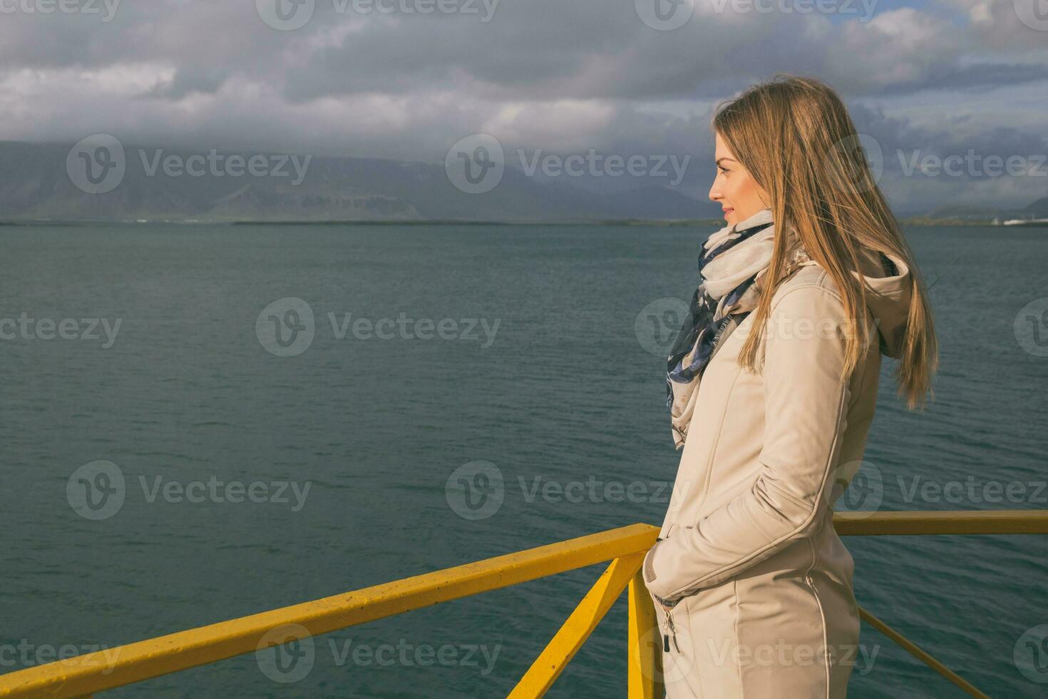 schön Frau Stehen beim das Hafen im Reykjavik und genießt suchen beim das meer.bild enthält wenig Lärm weil von hoch iso einstellen auf Kamera und es foto