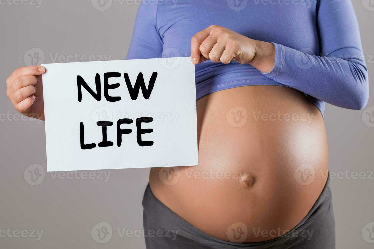 Bild von schließen oben Bauch von schwanger Frau halten Papier mit Text Neu Leben auf grau Hintergrund. foto