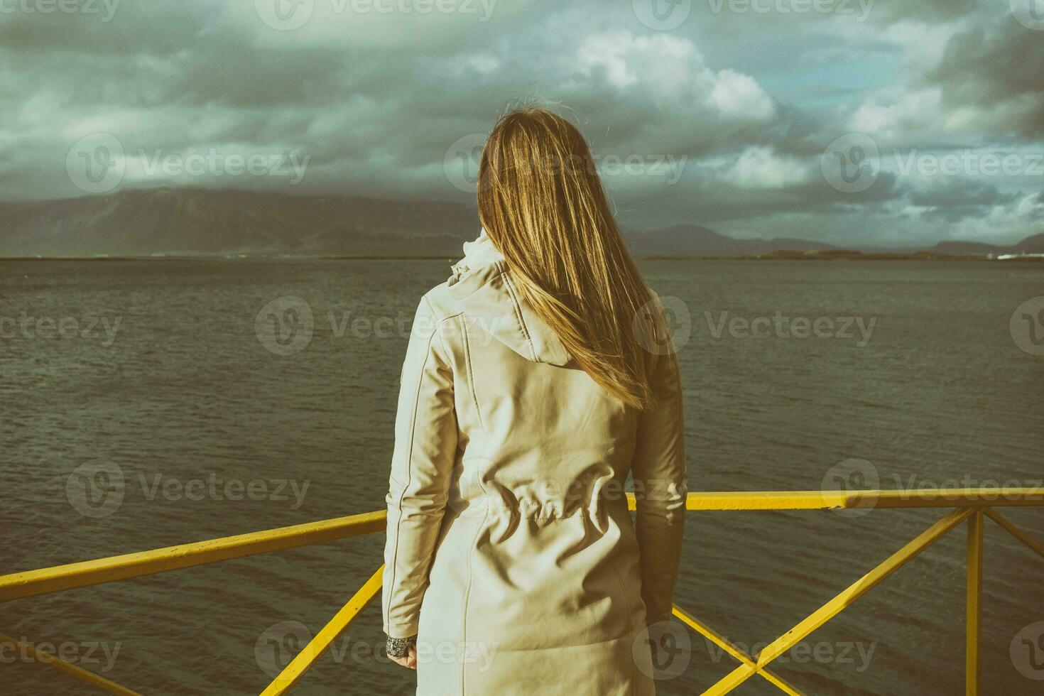 Frau Stehen beim das Hafen im Reykjavik und suchen beim das meer.bild enthält wenig Lärm weil von hoch iso einstellen auf Kamera und es ist getönt. foto