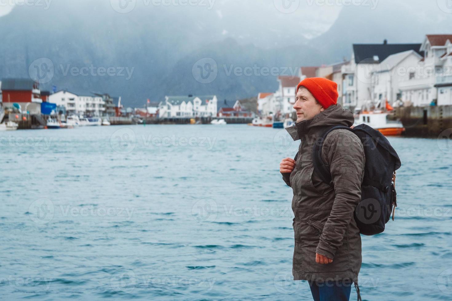 Reisender Mann mit Rucksack auf dem Hintergrund der Fischerhäuser Berg und See foto