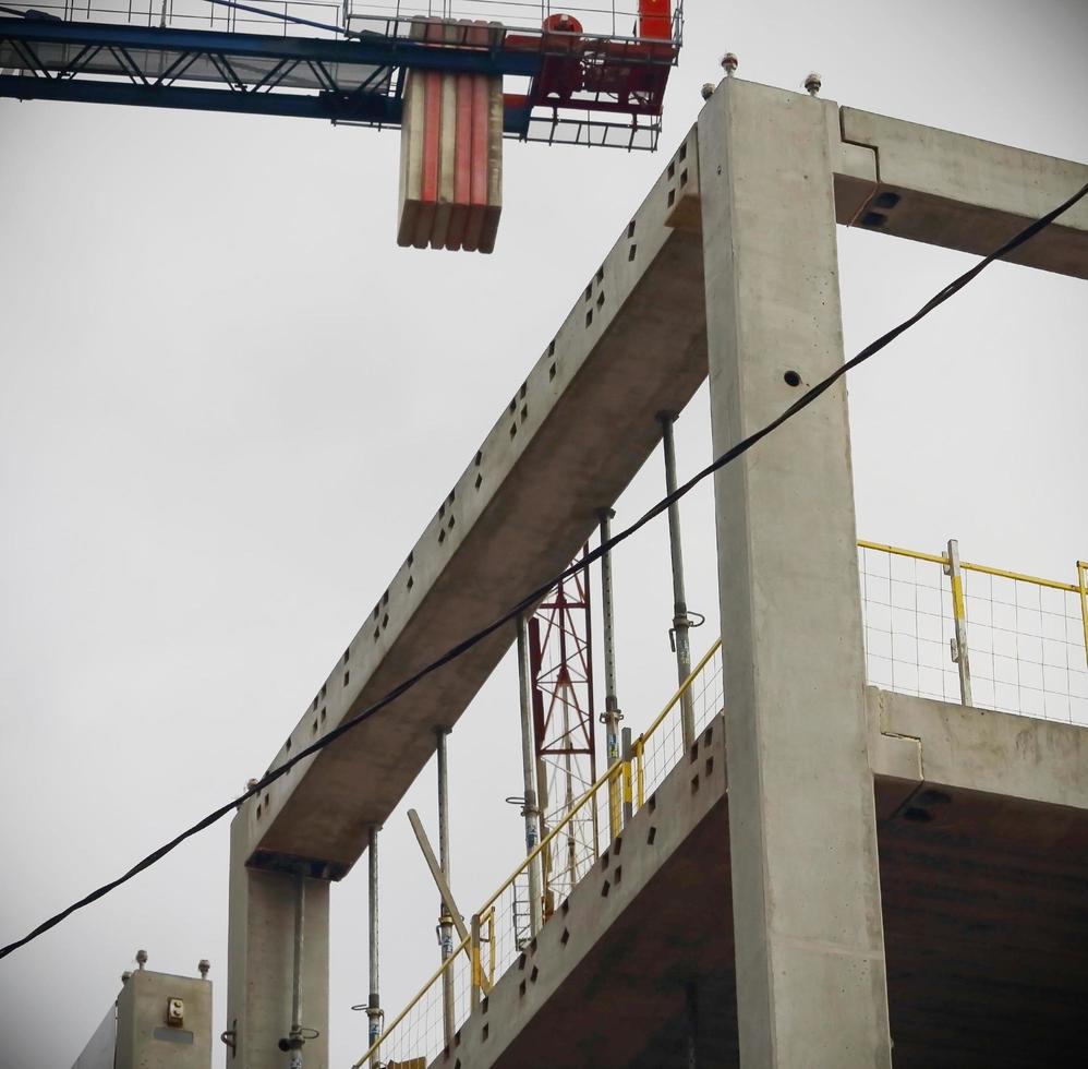 Baukran über Betonbaukörper am weißen Himmel foto