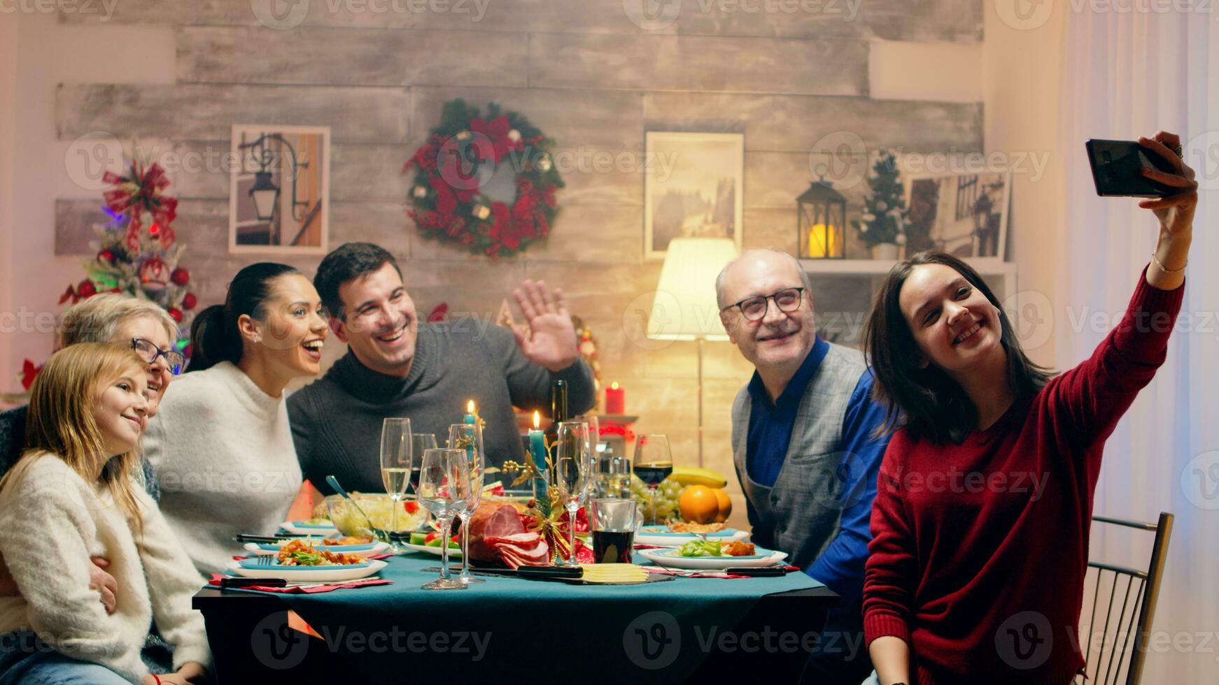 Teenager Tochter nehmen ein Selfie mit das Familie beim Weihnachten Wiedervereinigung. traditionell festlich Weihnachten Abendessen im Mehrgenerationenhaus Familie. genießen Weihnachten Mahlzeit Fest im dekoriert Zimmer. groß Familie Wiedervereinigung foto