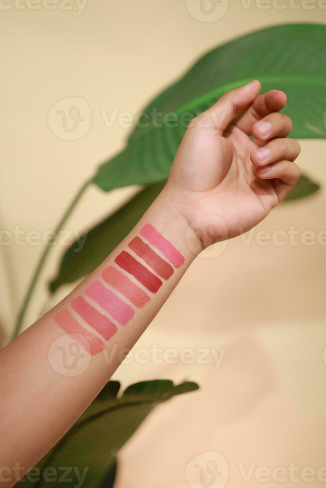 Lippenstift Farbfelder auf Frau Hand auf Beige Hintergrund. Lippenstift Farbe Arm Anzeige Kontrast foto