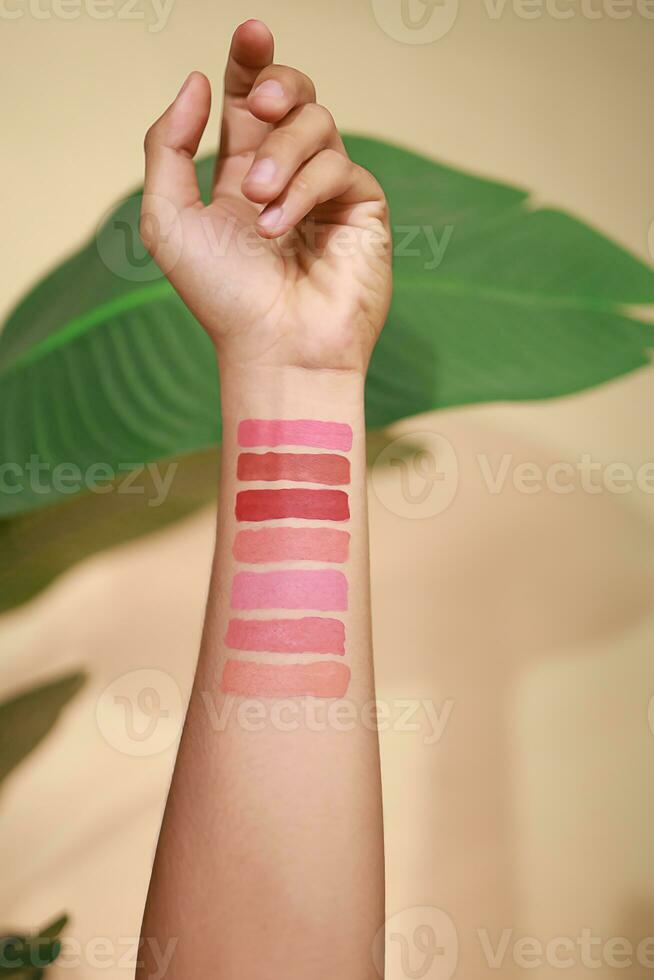 Lippenstift Farbfelder auf Frau Hand auf Beige Hintergrund. Lippenstift Farbe Arm Anzeige Kontrast foto