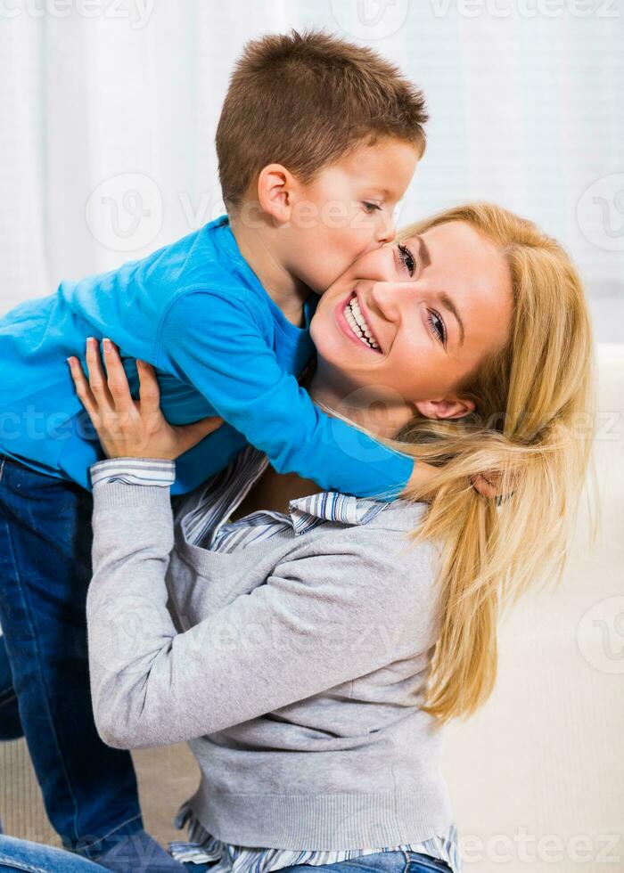 glücklich Mutter halten ihr Sohn während er ist küssen ihr. foto