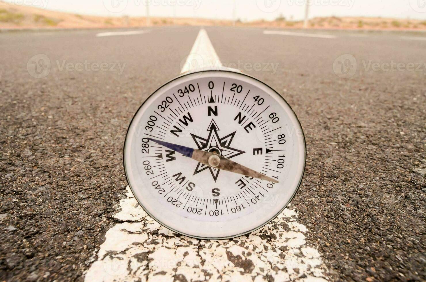 ein Kompass ist platziert auf das Asphalt von ein Straße foto