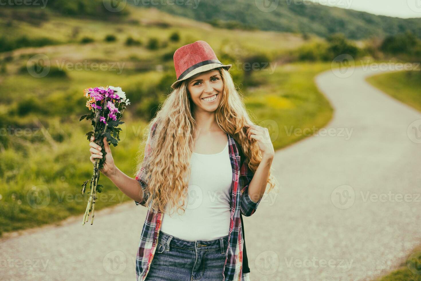 Frau halten Strauß von Blumen beim das Land Straße. foto