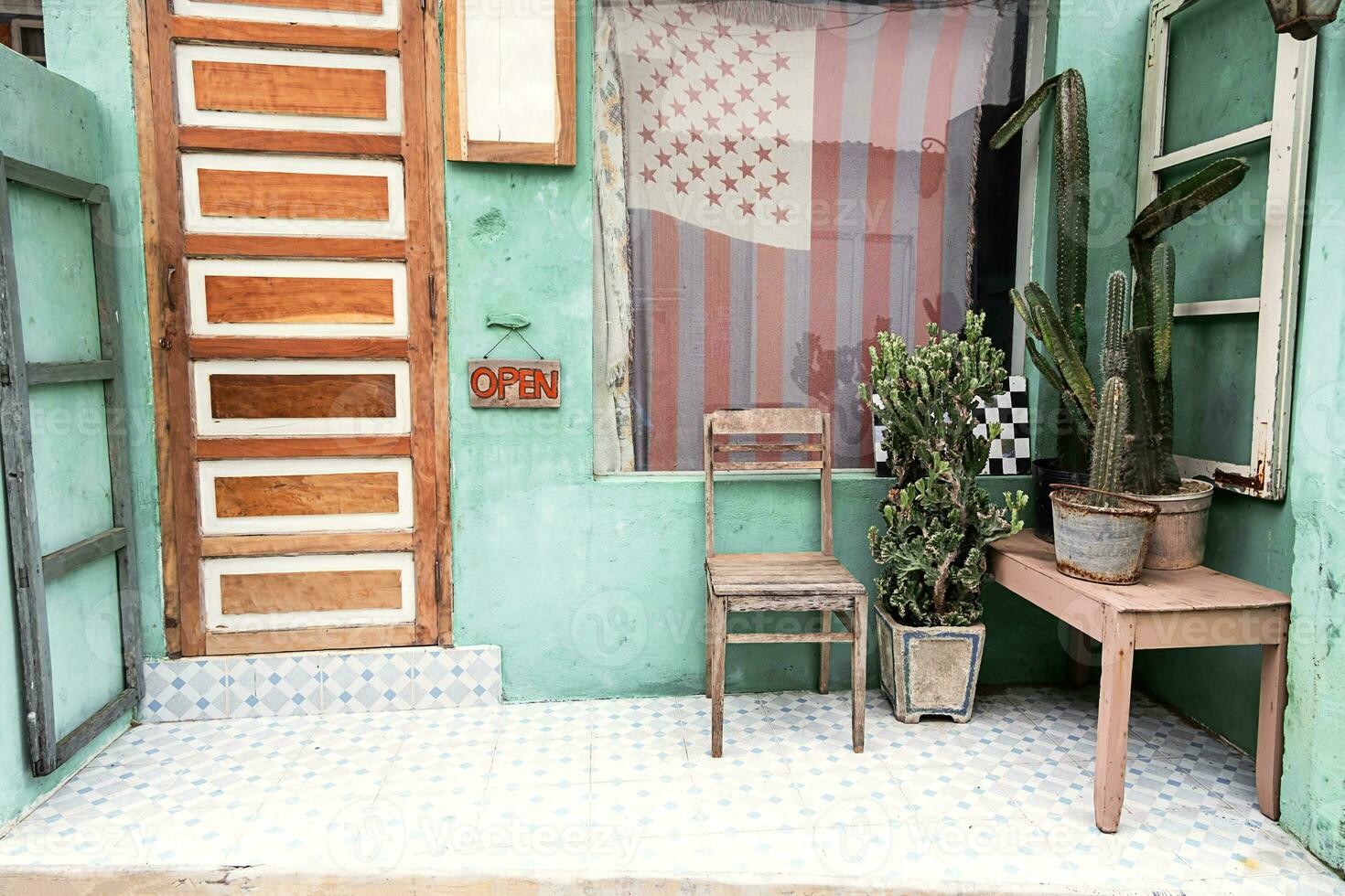 alt Stuhl und Kakteen in der Nähe von Vorderseite Tür von klein Jahrgang Land speichern. foto