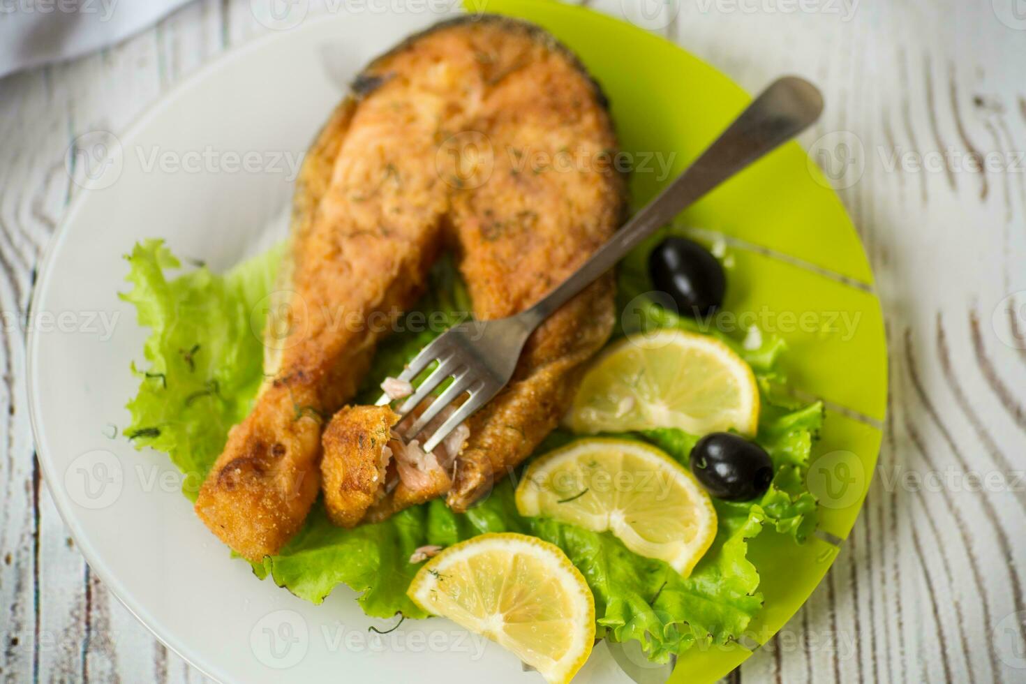 Stück von gebraten Lachs Fisch im ein Teller mit Zitrone foto