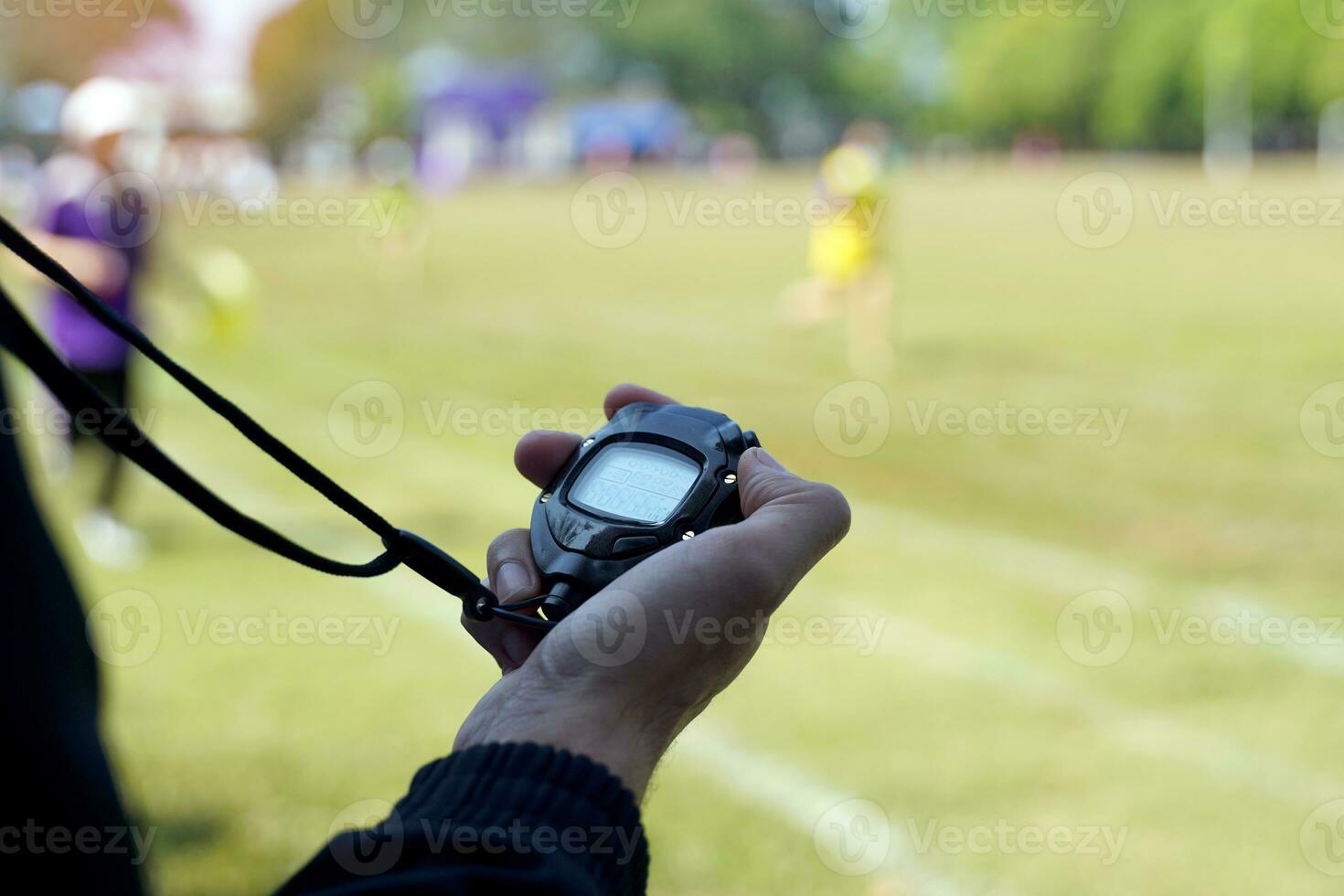 das Trainer zeitgesteuert das Fertig Linie mit ein Stoppuhr zu bestimmen das Gewinner von das Schule Sport Tag Laufen Fall. Sanft und selektiv Fokus. foto