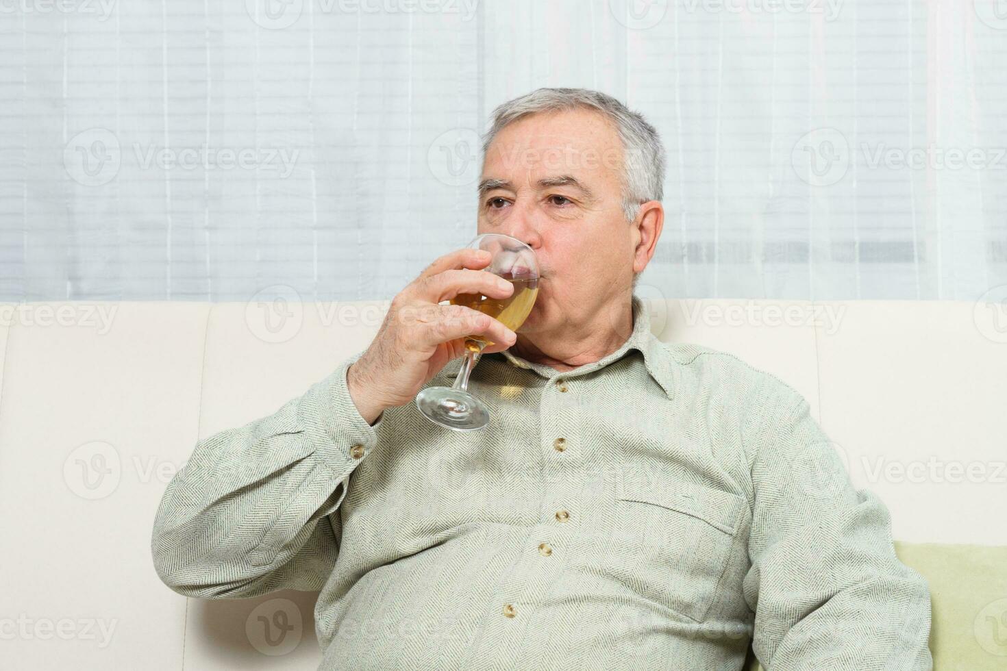 Senior Mann genießt Trinken Wein beim heim. foto