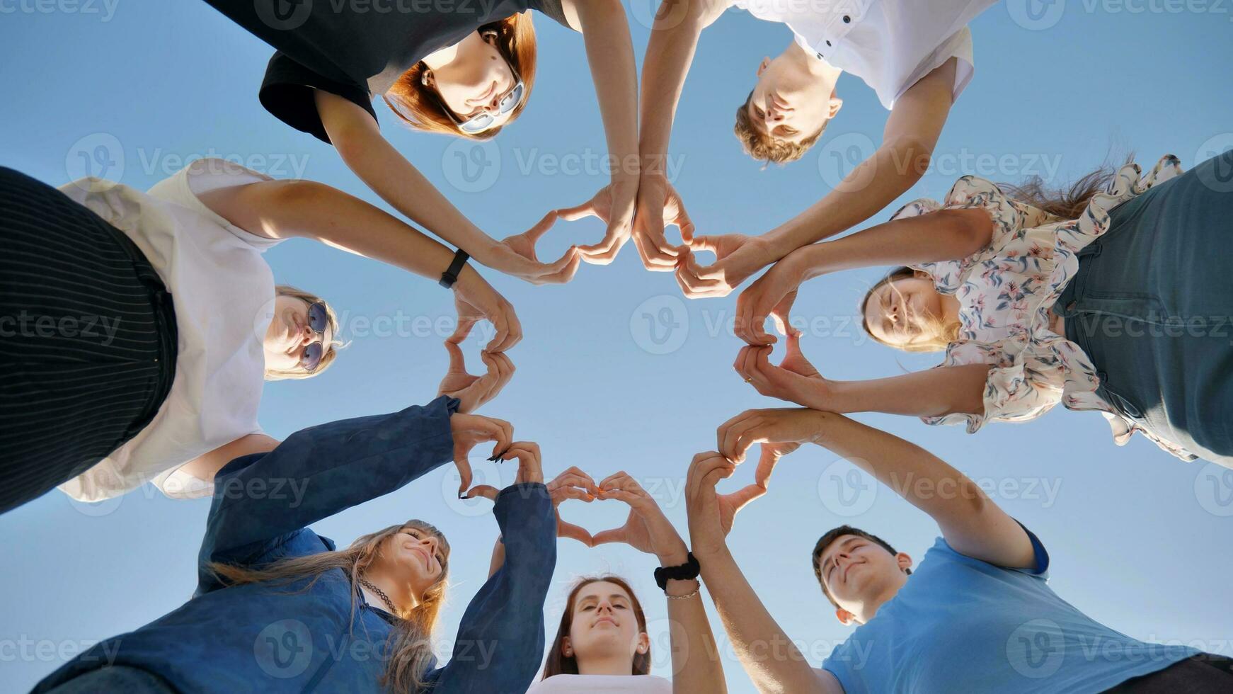 jung freunde Stand im ein Kreis und machen Herzen aus von ihr Hand Handgelenke. foto