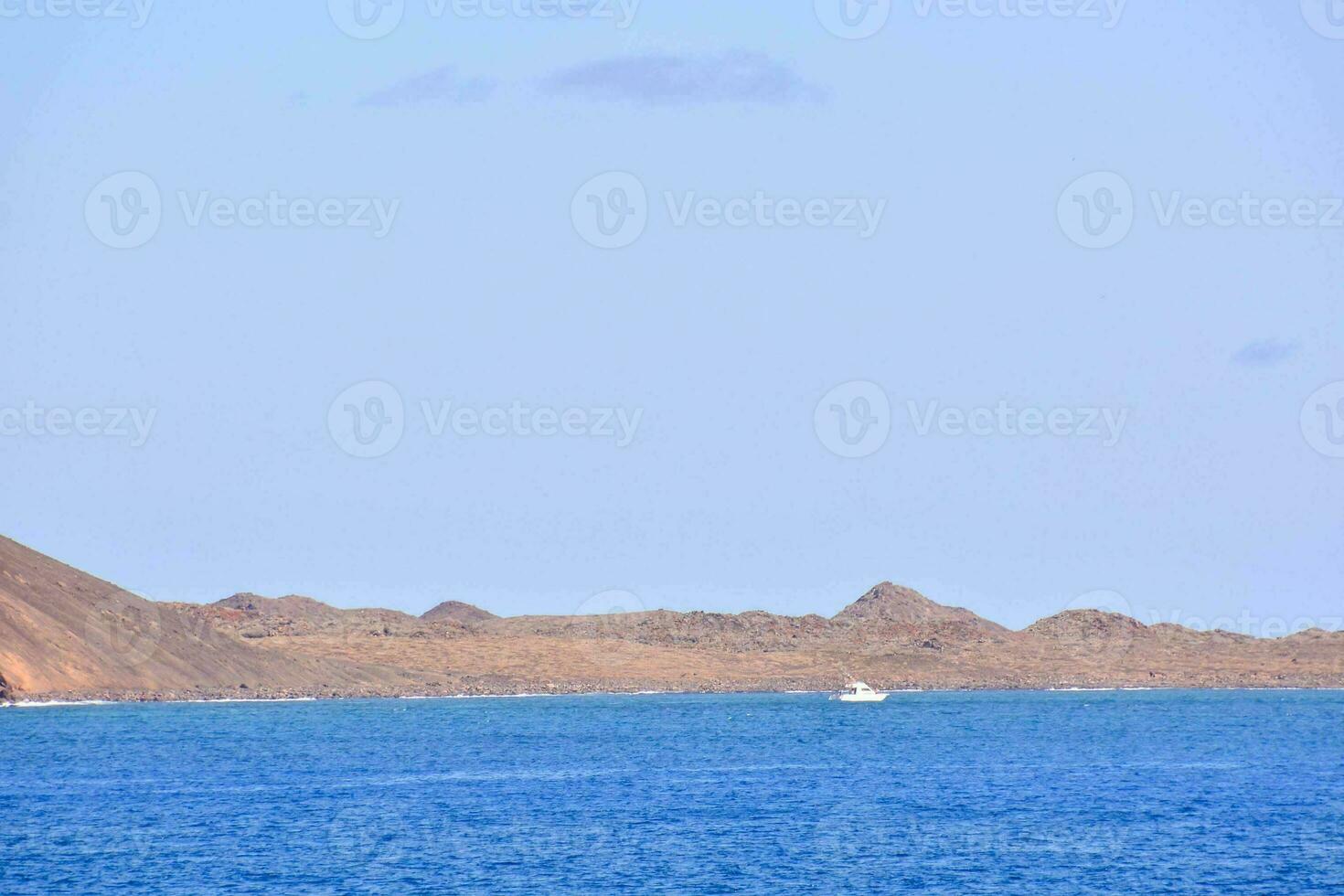 ein Boot ist aus im das Ozean in der Nähe von ein felsig Insel foto