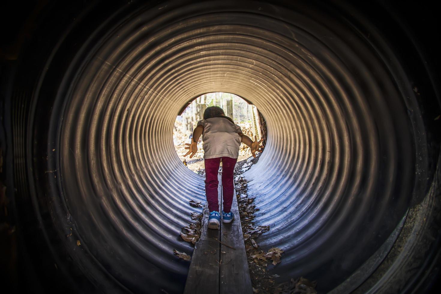 kleines Kind geht durch einen Tunnel auf einem Spielplatz foto