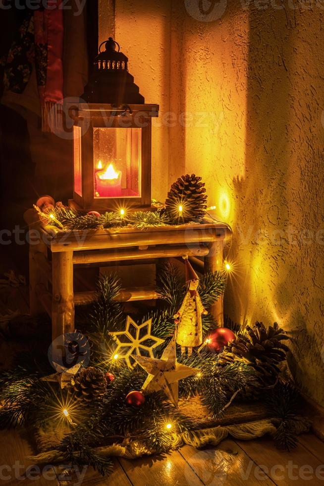 Weihnachtsdekoration mit Kerze, Tannenzweigen, Weihnachtsmann und Glaskugeln vor dunklem Hintergrund foto