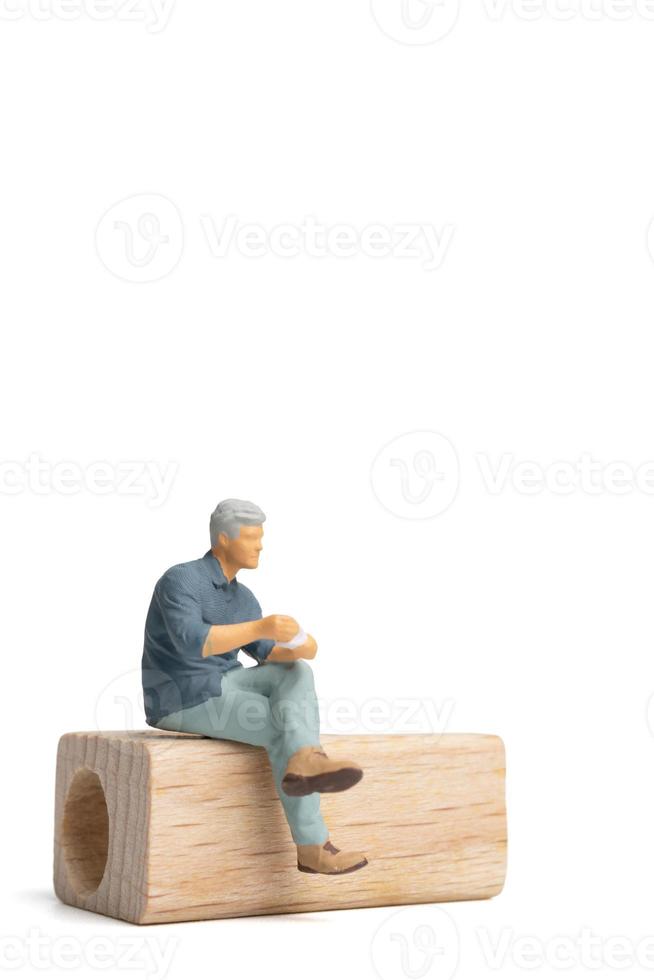 Miniatur-Leute-Geschäftsmann sitzt auf Holzstuhl isoliert auf weißem Hintergrund foto