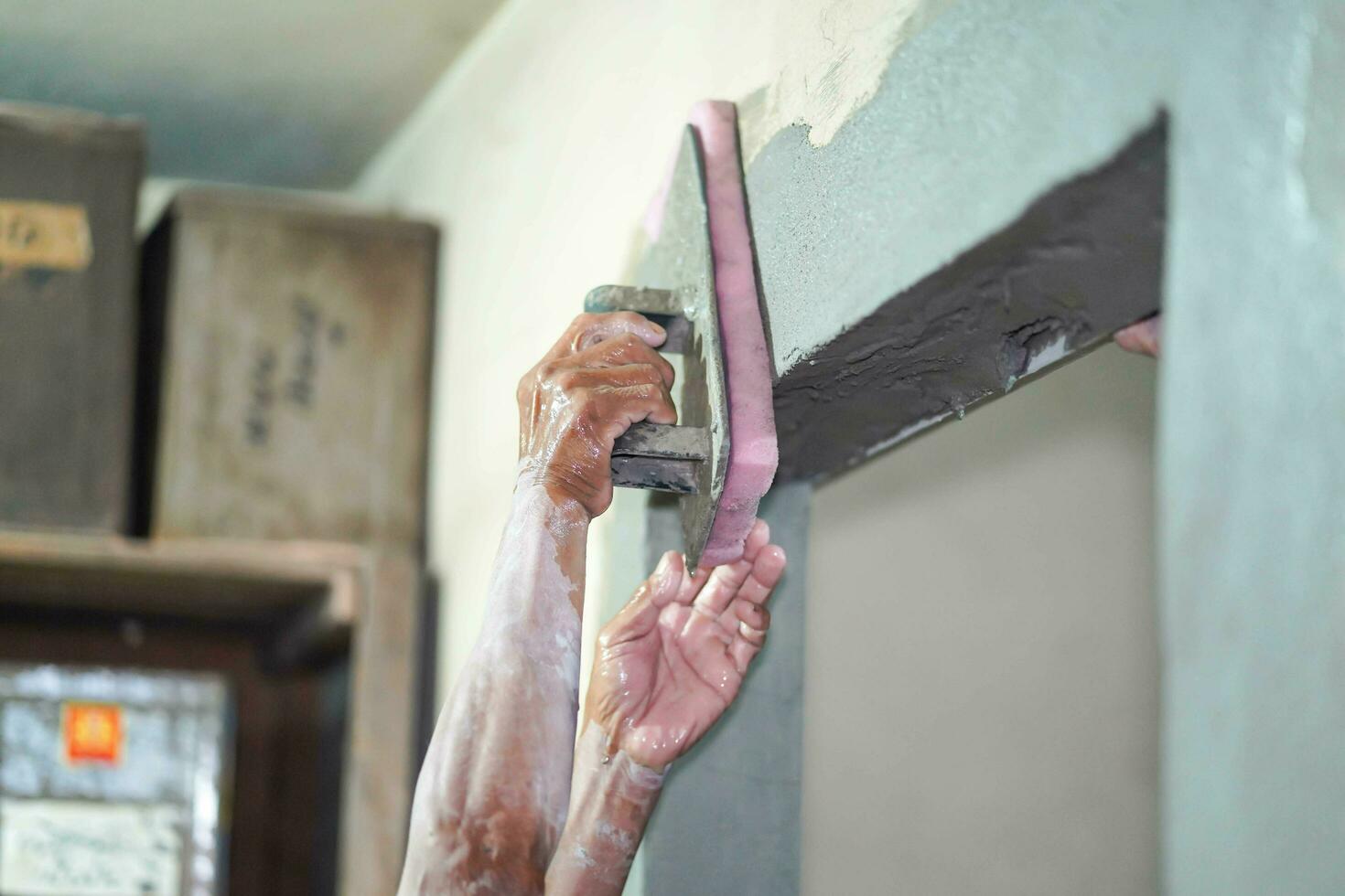 Nahansicht Hände von Baumeister halten Granatwerfer schwenken und Schwamm Verputzen Wände mit Zement im Konstruktion Seite? ˅. mit ein Schwamm zu Gips auf das Mauer hilft zu glatt das verputzt Bereich. Mehr schön foto